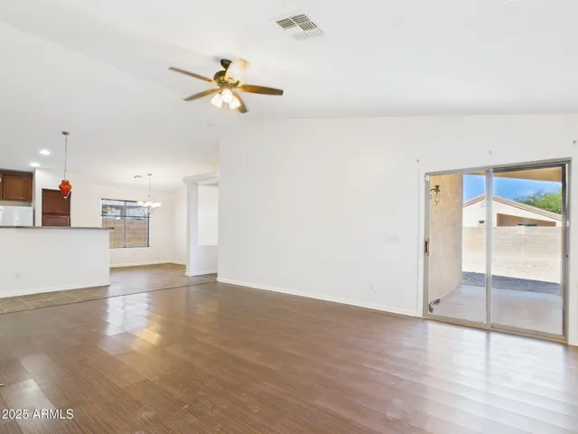 a view of empty room with wooden floor and ceiling fan