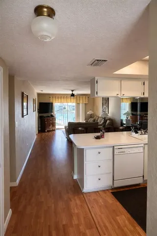 a kitchen with stainless steel appliances granite countertop a stove a sink a refrigerator and white cabinets with wooden floor