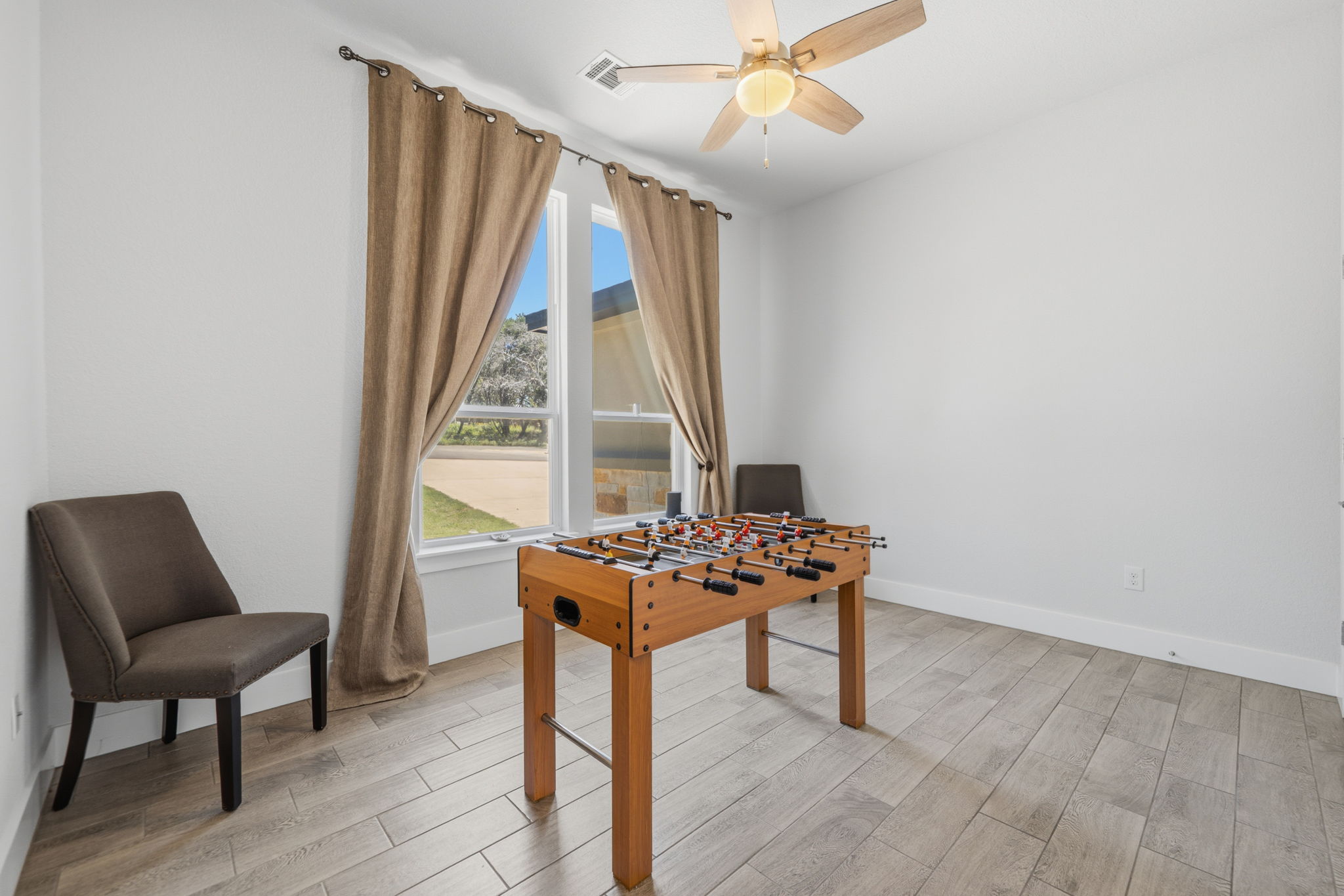 18605 Masters Cove Point Venture, TX 78645 - Photo 5 of 40 Spacious interior room featuring wood-finish tile flooring, a ceiling fan with integrated lighting, and two large windows with curtain rods