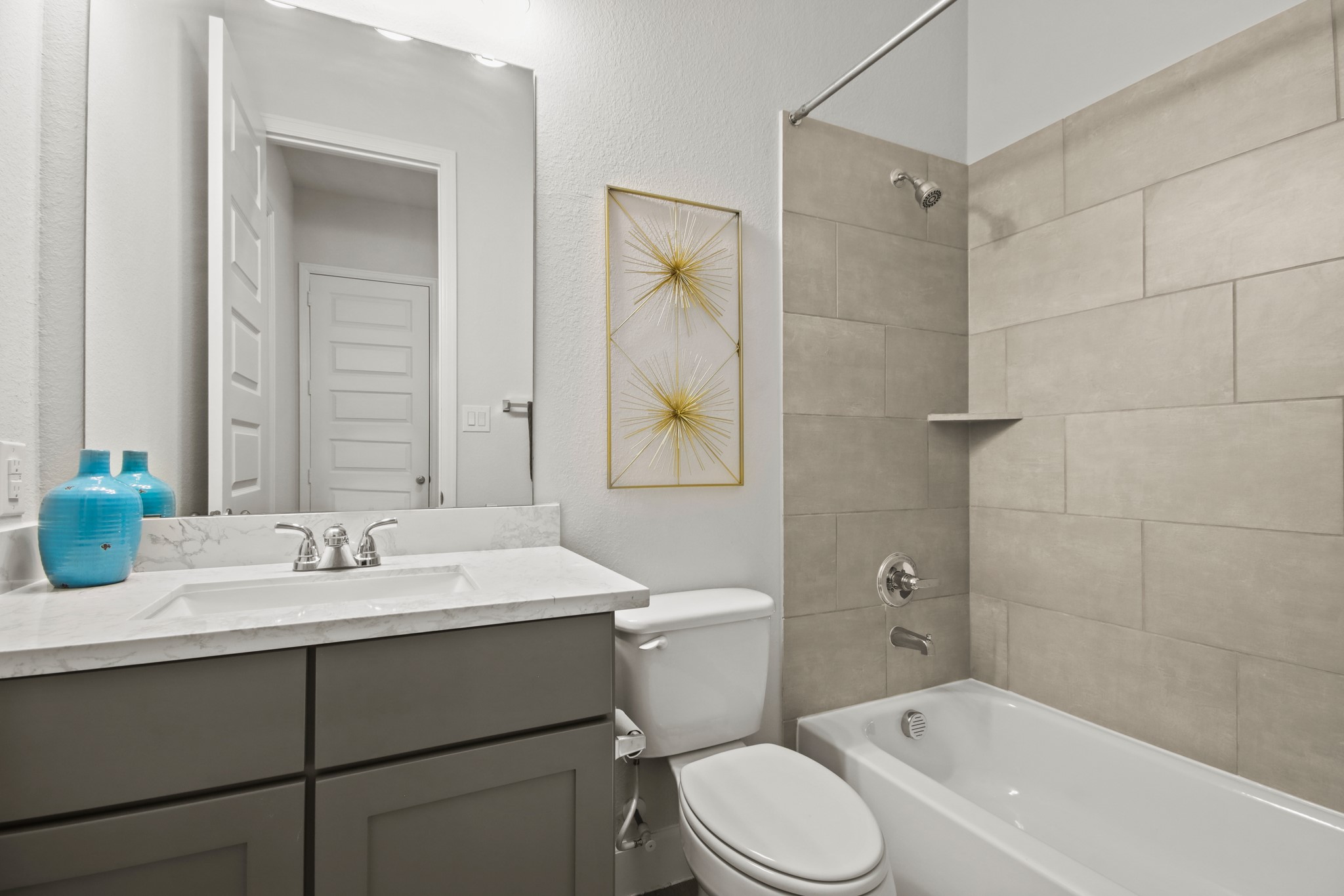 17406 Bayflower Conroe, TX 77385 - Photo 22 of 35 Secondary bathroom features a modern design with a sleek vanity, marble countertop, and stylish fixtures. The shower-tub combo is accented by large, neutral tiles.