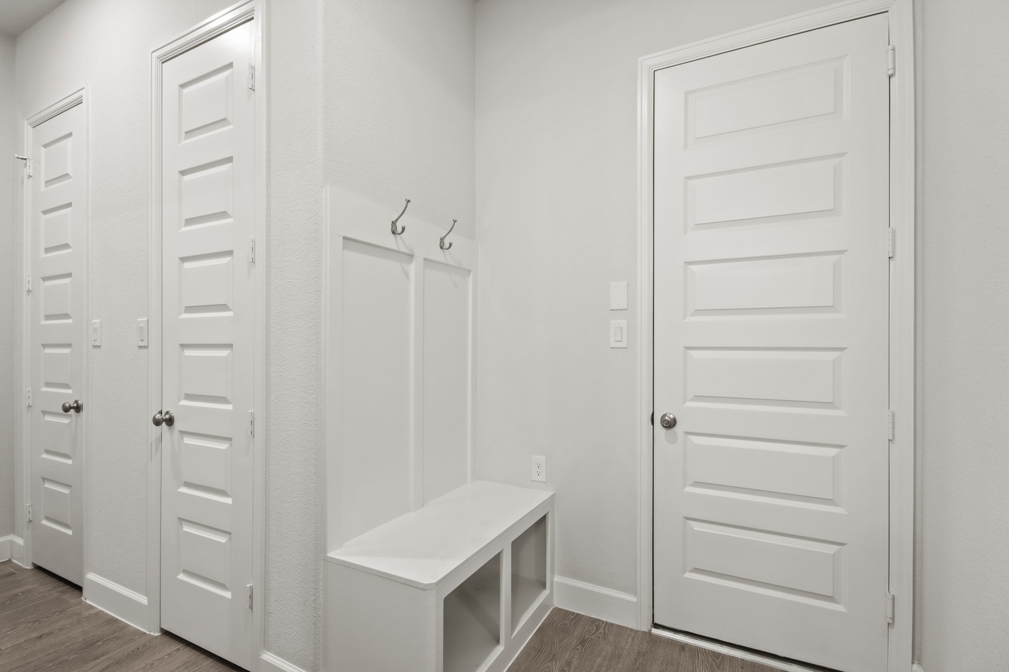 17406 Bayflower Conroe, TX 77385 - Photo 23 of 35 Modern hallway with three paneled doors and a built-in bench, ideal for storage and organization.