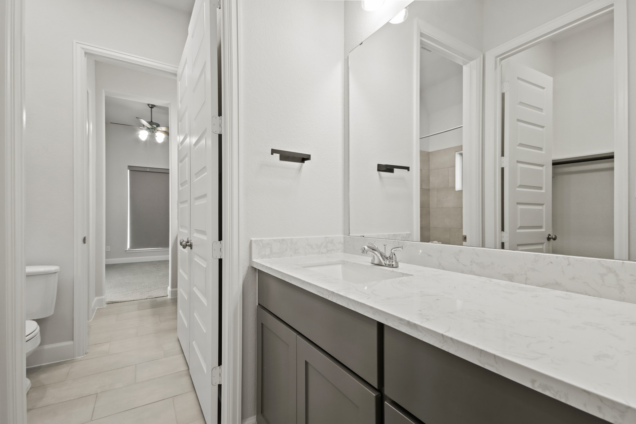 17406 Bayflower Conroe, TX 77385 - Photo 25 of 35 Modern secondary bathroom with sleek marble countertop, ample storage, and acress into a secondary bedroom. The neutral color palette and contemporary fixtures add a stylish touch.