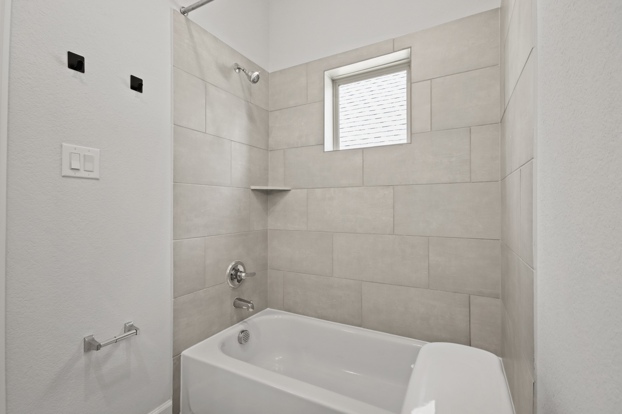 17406 Bayflower Conroe, TX 77385 - Photo 27 of 35 Secondary bathroom features a shower/tub combo with neutral tiled walls, and window for natural light.