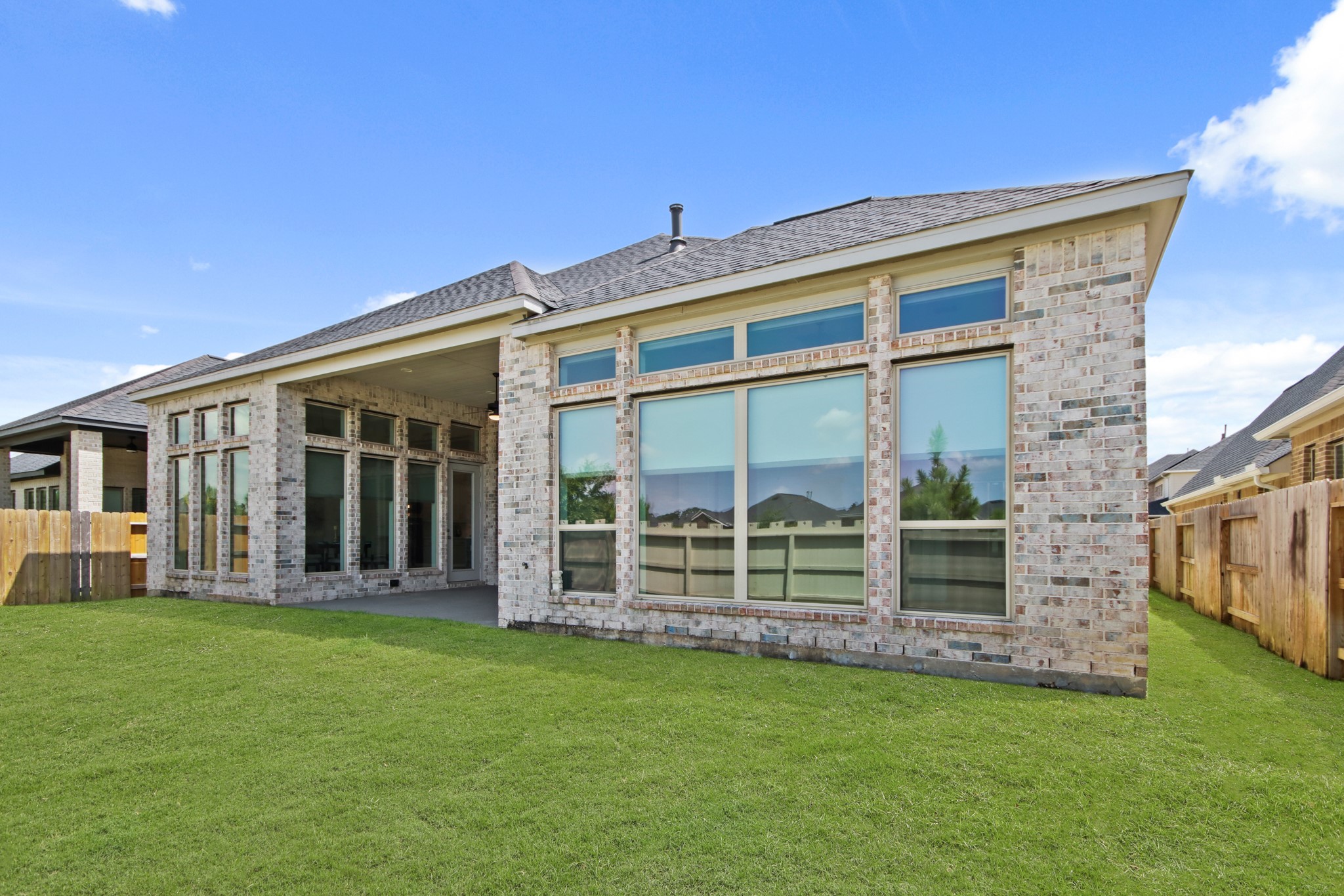 17406 Bayflower Conroe, TX 77385 - Photo 34 of 35 Large windows and covered area, this patio is set on a lush green lawn. The design is contemporary, offering plenty of natural light and outdoor space.