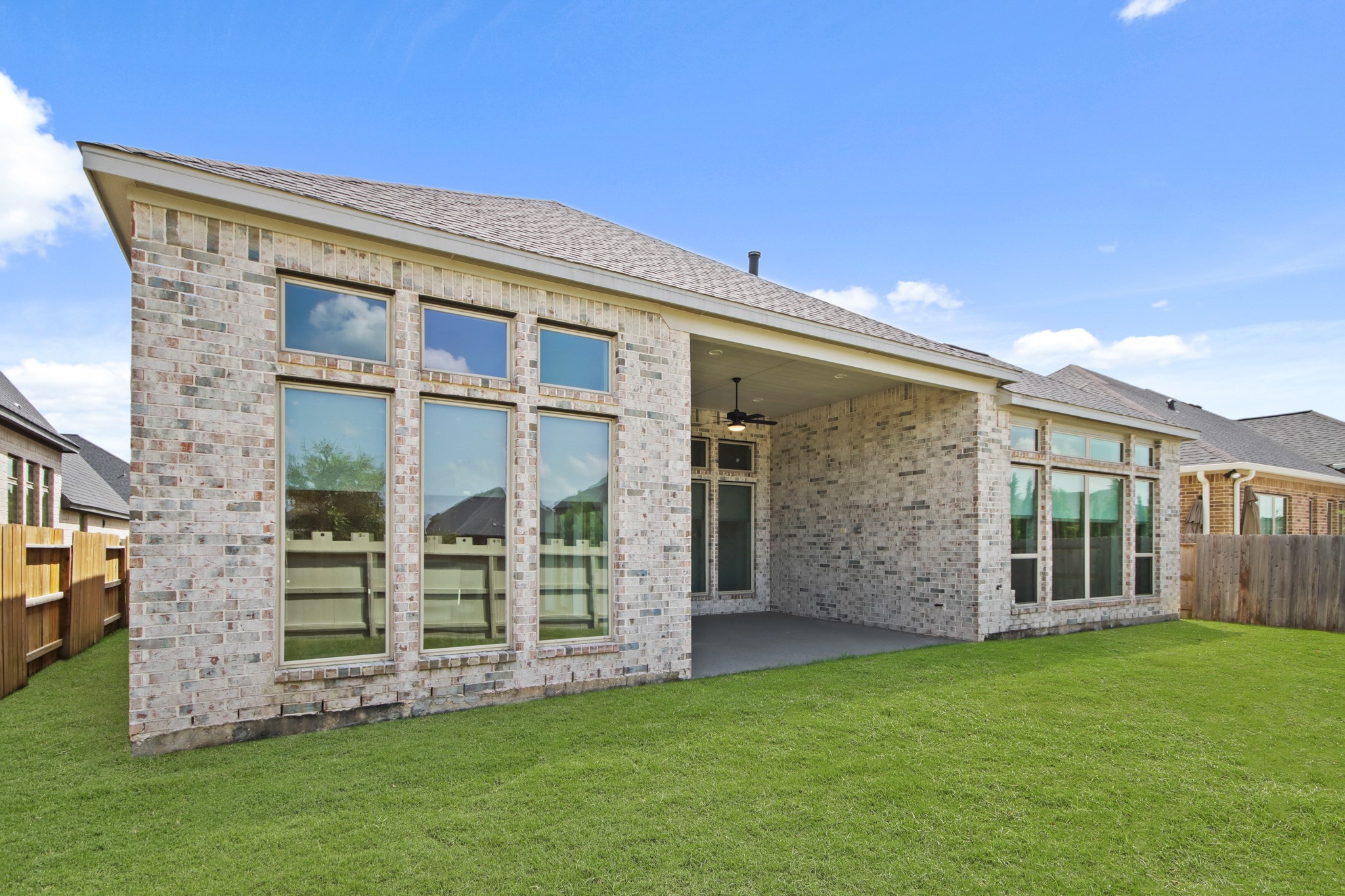 17406 Bayflower Conroe, TX 77385 - Photo 35 of 35 Large, tall wall of windows and a spacious covered patio. The backyard is grassy and fenced, offering a private outdoor space.
