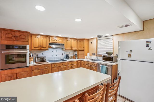 a large kitchen with cabinets wooden floor and stainless steel appliances
