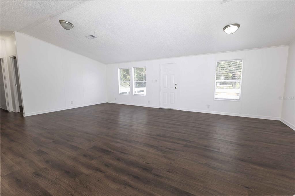 4872 Evans Street Coleman, FL 33521 - Photo 6 of 24 an empty room with wooden floor and windows