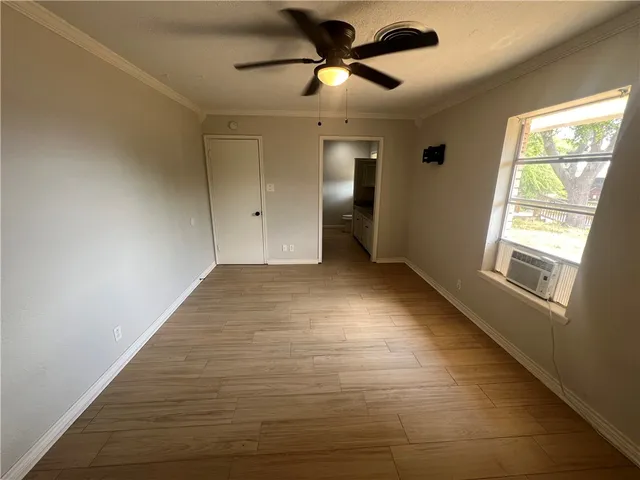 a view of empty room with wooden floor and fan