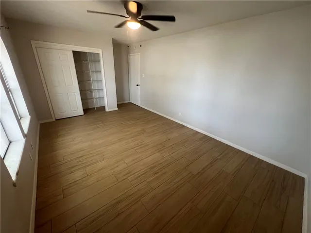 an empty room with closet and a ceiling fan