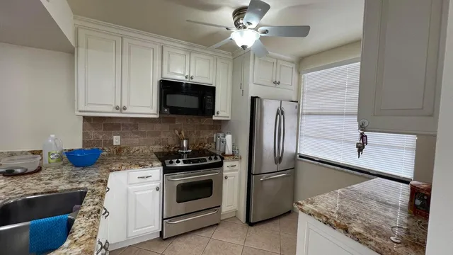 a kitchen with stainless steel appliances granite countertop a sink stove microwave and refrigerator
