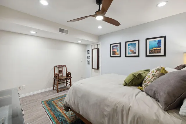 a bedroom with a bed painting on wall and a desk