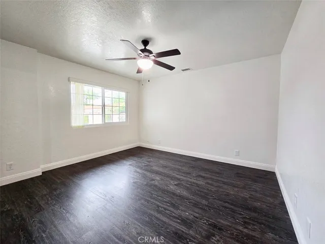 an empty room with wooden floor fan and windows