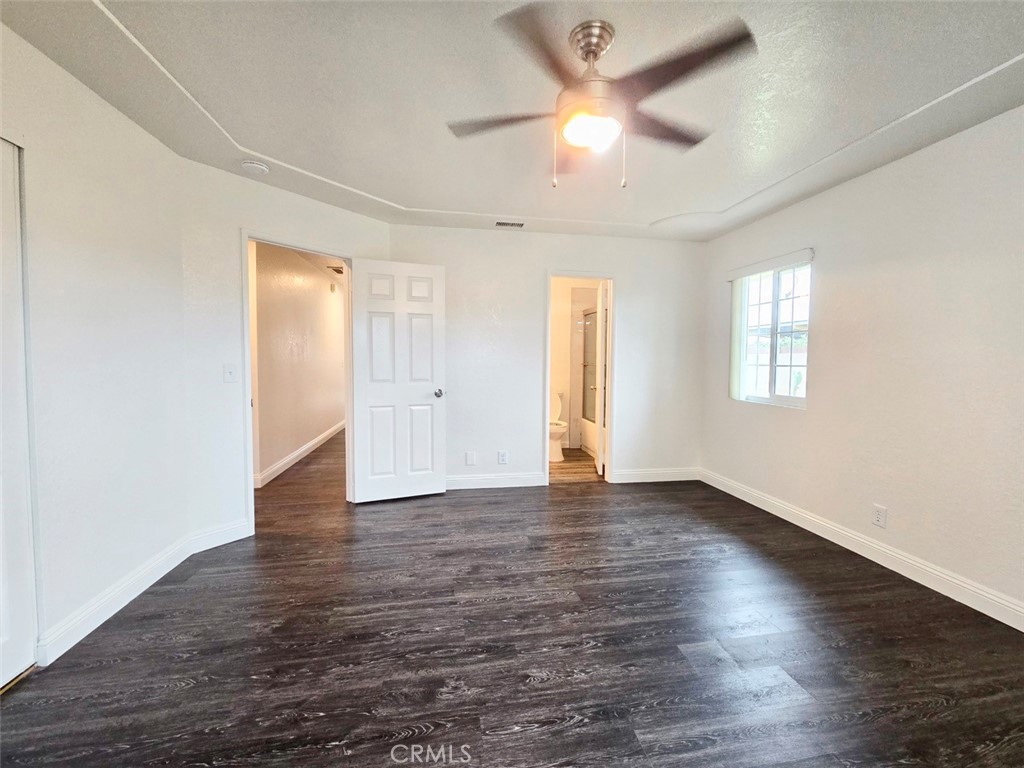 7352 Nada Street Downey, CA 90242 - Photo 17 of 28 an empty room with wooden floor ceiling fan and windows