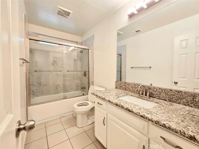 a bathroom with a granite countertop sink a toilet a mirror and shower