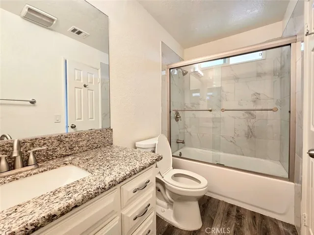 a bathroom with a granite countertop sink toilet and shower