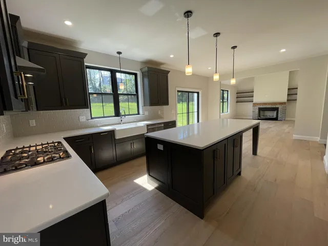 an open kitchen with stainless steel appliances granite countertop a sink a stove and a wooden floor