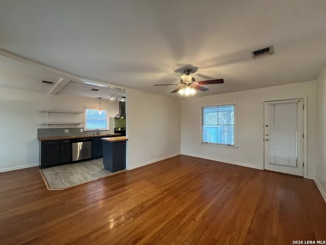 a view of kitchen and empty room with wooden floor