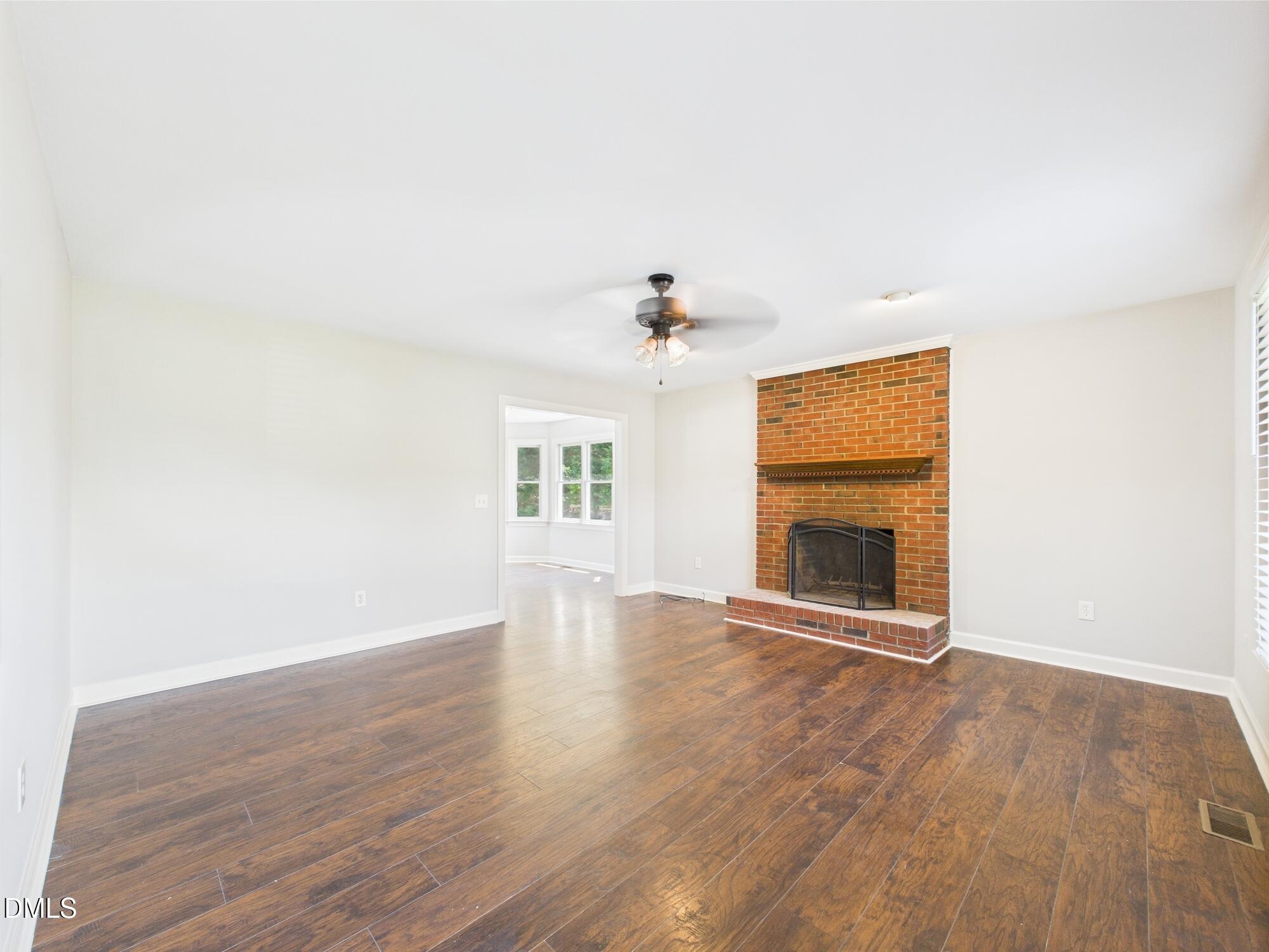 10917 Fanny Brown Road Raleigh, NC 27603 - Photo 13 of 54 an empty room with wooden floor fireplace and windows