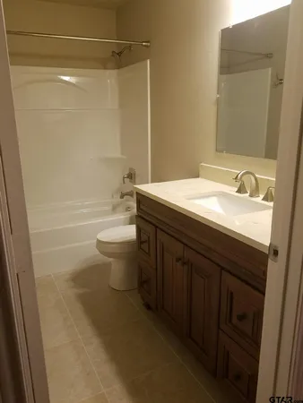 a bathroom with a granite countertop sink a toilet and a mirror