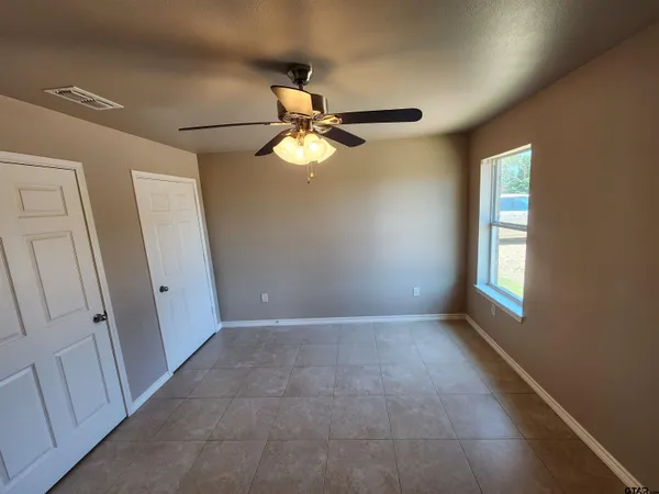 an empty room with windows and fan