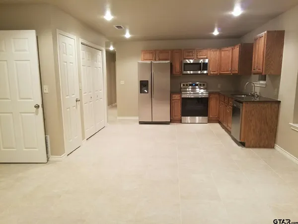 a large kitchen with a large counter top stainless steel appliances and cabinets