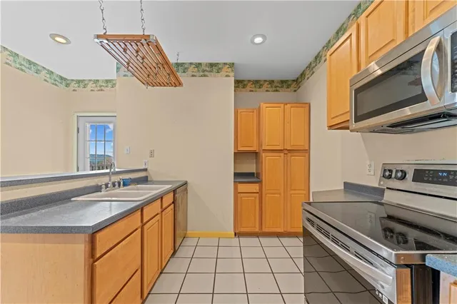 a kitchen with stainless steel appliances granite countertop a refrigerator a stove and a sink with wooden floor