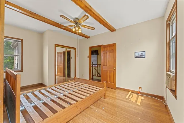 a bedroom with wooden floor closet and a bathroom