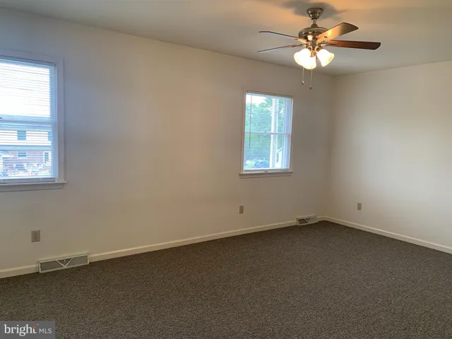 an empty room with windows and fan