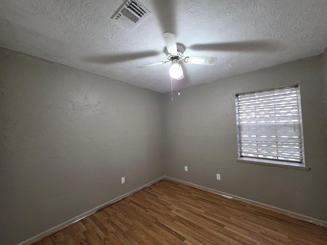 2414 Goldenrod Street Highlands, TX 77562 - Photo 9 of 18 an empty room with wooden floor fan and windows