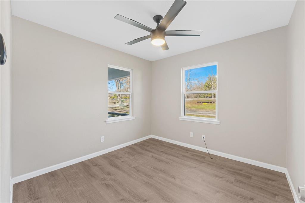 9521 Dalrock Road Rowlett, TX 75089 - Photo 13 of 38 an empty room with wooden floor ceiling fan and windows