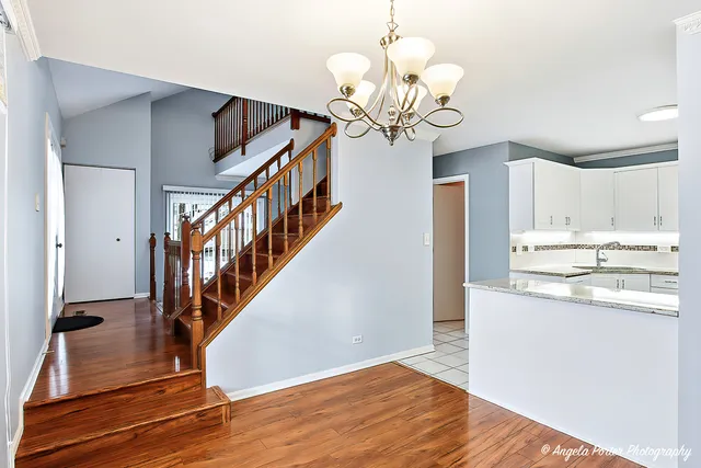 a view of a hallway with wooden floor and chandelier