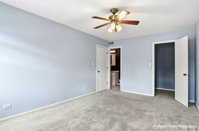 an empty room with closet and a chandelier fan