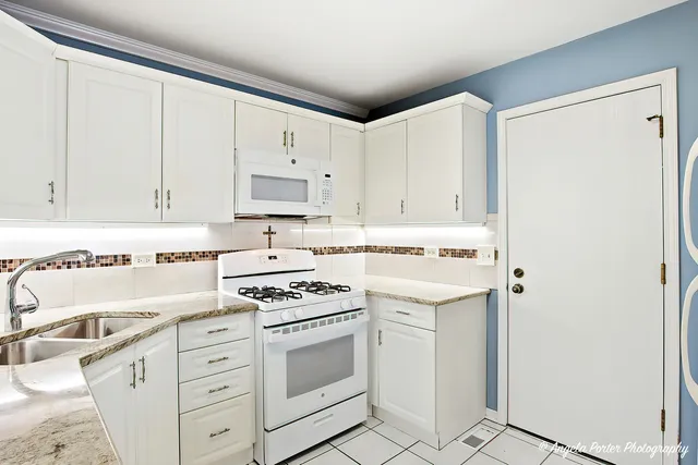 a kitchen with granite countertop white cabinets and white appliances