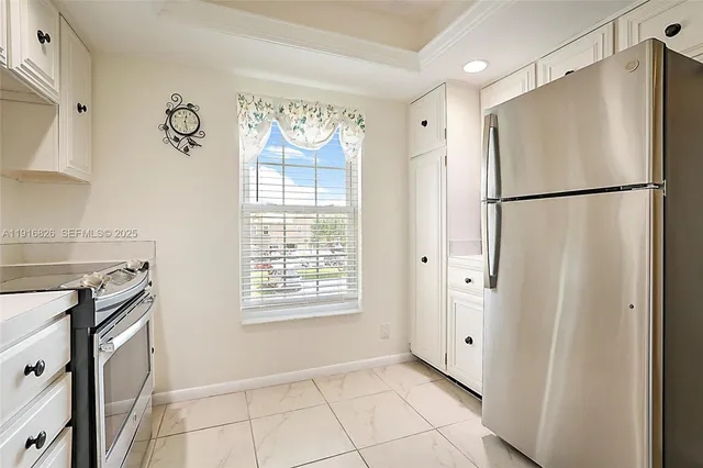 a kitchen with white cabinets and refrigerator