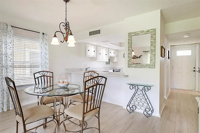 a view of a dining room and livingroom with furniture wooden floor a chandelier