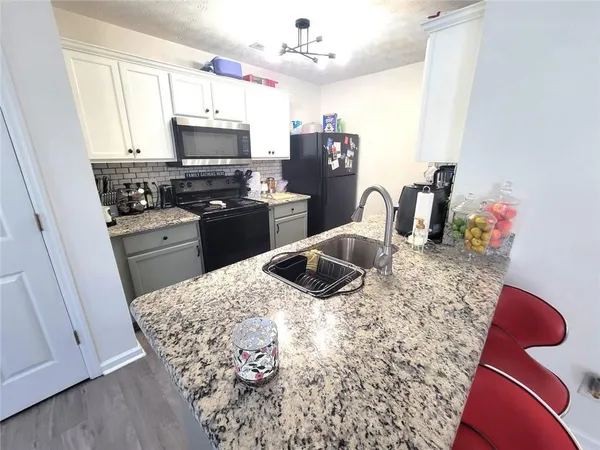 a kitchen with granite countertop a sink stove and refrigerator