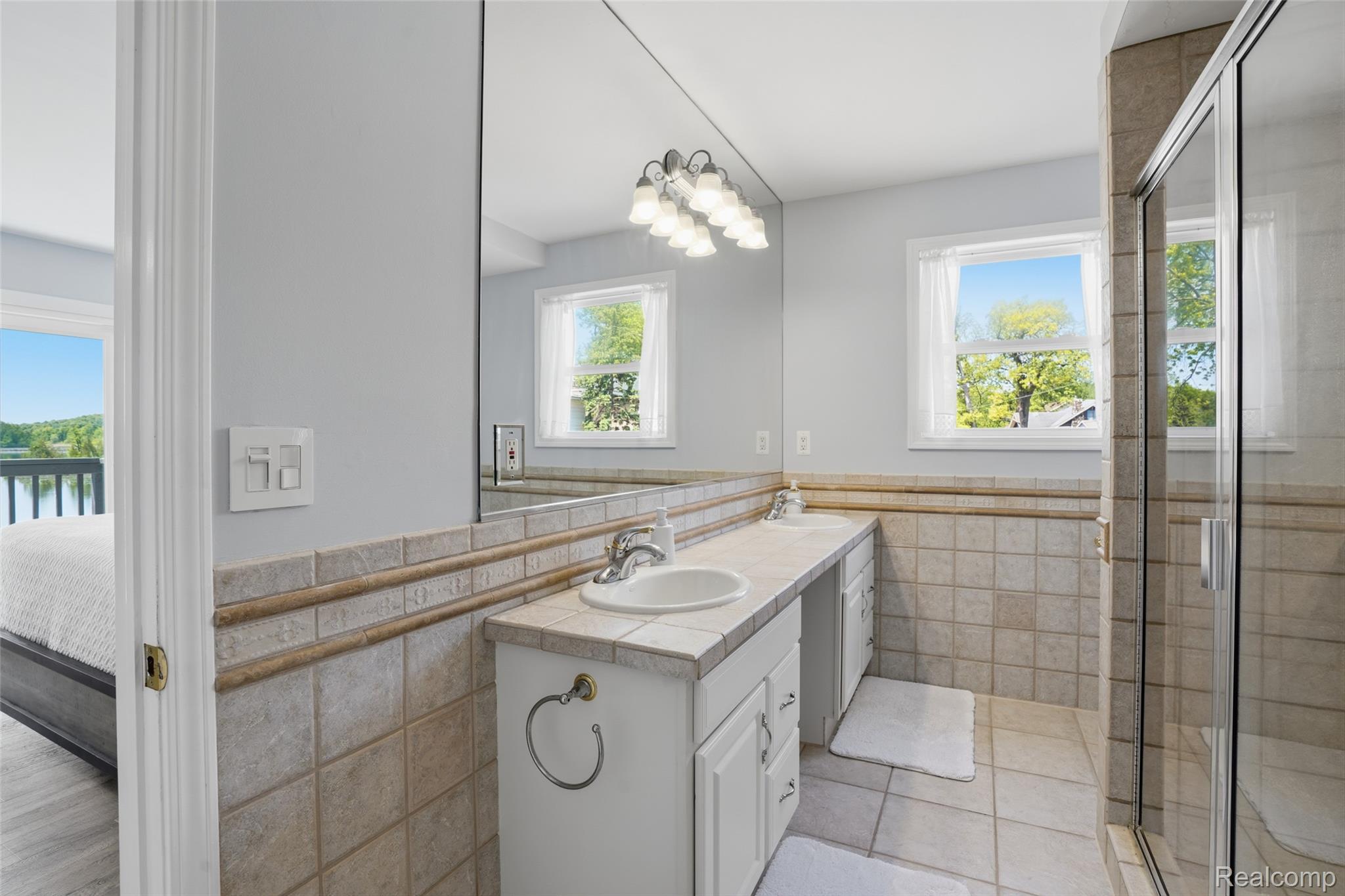 7217 Andersonville Road Clarkston, MI 48346 - Photo 30 of 65 Bathroom featuring a double vanity with integrated sinks, tile countertop, and white cabinetry