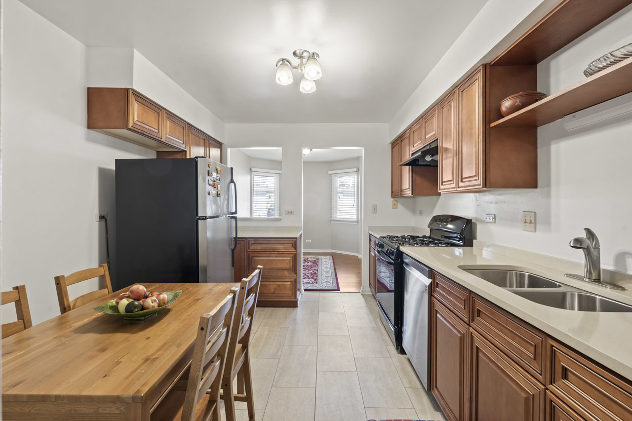 1265 Ranchview Court Buffalo Grove, IL 60089 - Photo 9 of 24 a kitchen with stainless steel appliances granite countertop a sink dishwasher a refrigerator a stove and a dining table with wooden floor