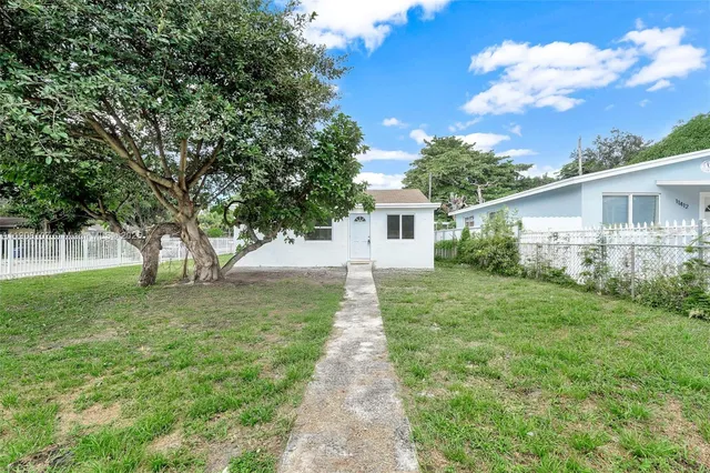 a view of a yard in front of a house with large trees