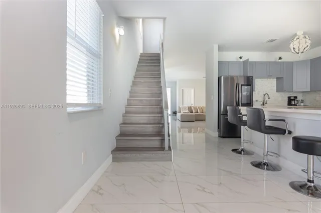 a kitchen with stainless steel appliances kitchen island granite countertop a refrigerator and a sink