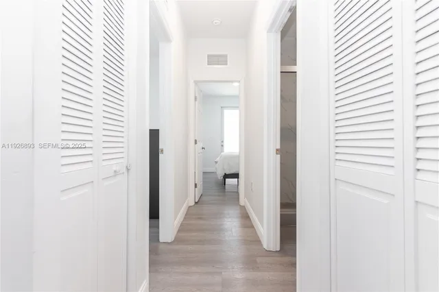 a view of a hallway with wooden floor and a bathroom
