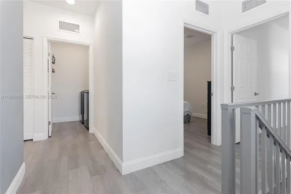 a view of a hallway with wooden floor and a bathroom
