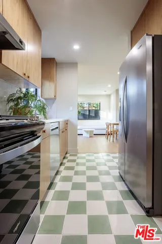 a kitchen with stainless steel appliances kitchen island granite countertop a refrigerator and a sink