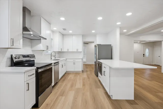a kitchen with kitchen island a sink a stove oven a counter top space and cabinets
