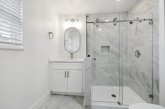 a bathroom with a shower a mirror and a window