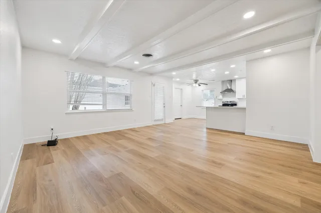 a view of empty room with wooden floor and window