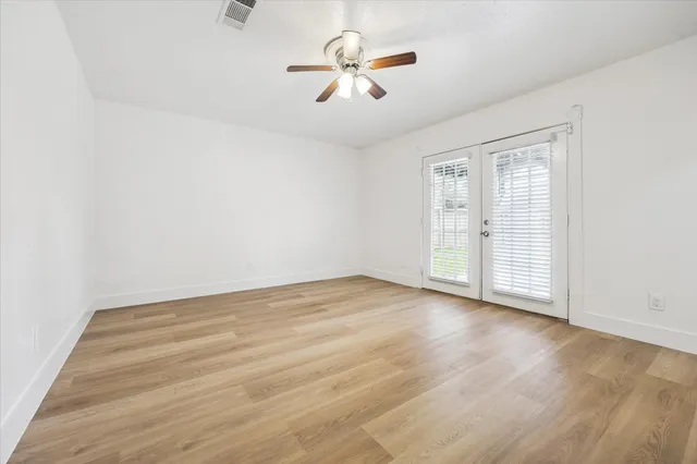 an empty room with wooden floor and fan
