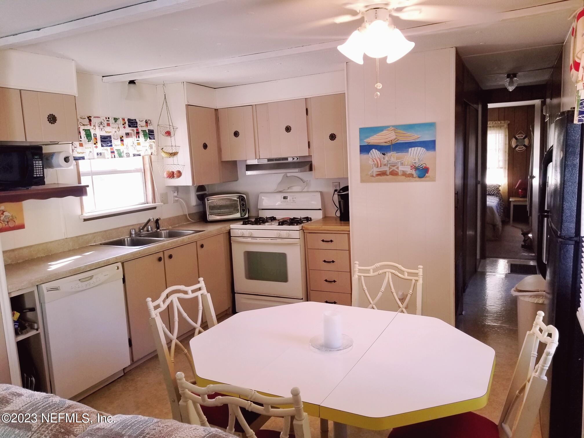 116 Douglas Street Crescent City, FL 32112 - Photo 7 of 26 a kitchen with stainless steel appliances granite countertop a stove a refrigerator a sink dishwasher a dining table and chairs with wooden floor