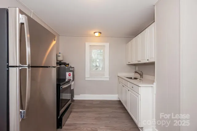 a kitchen with stainless steel appliances granite countertop a refrigerator a sink and white cabinets