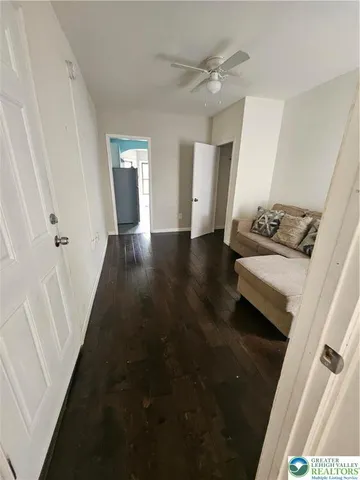 a view of a hallway to a livingroom with furniture wooden floor and window